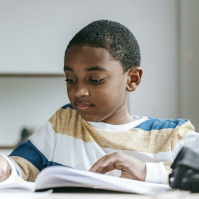 Positive black boy doing homework in copybook